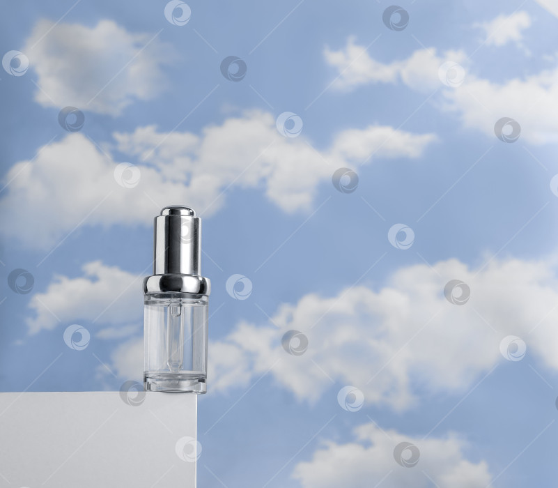 Скачать Прозрачная сыворотка на белом подиуме на фоне облачного голубого неба. Концепция легкости косметики фотосток Ozero
