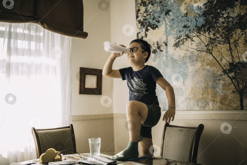 Скачать Маленький мальчик-студент стоял, положив ногу на стол, как пират с подзорной трубой. фотосток Ozero