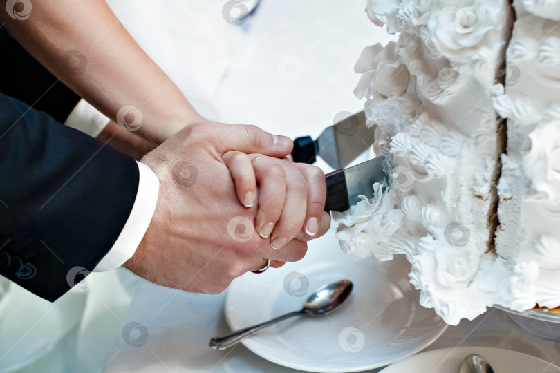 Скачать Мужская и женская руки вместе разрезают праздничный торт ко дню рождения. Праздничная сладкая еда фотосток Ozero