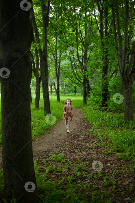 Скачать Девочка бежит по тропинке среди деревьев в парке фотосток Ozero