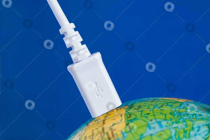 Скачать Белый USB-кабель подключен к глобусу. Концепция фотосток Ozero