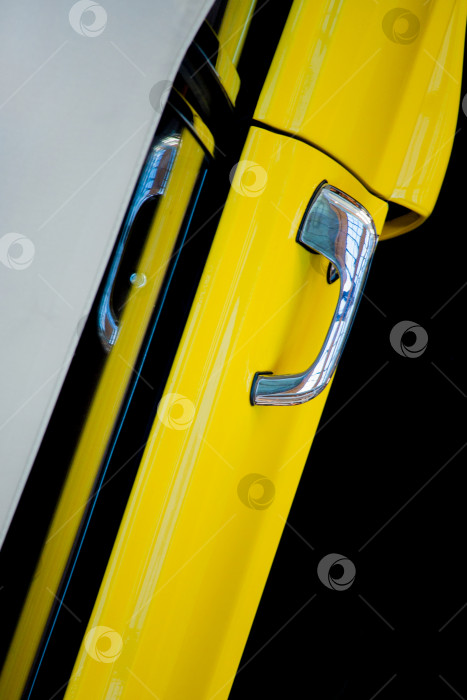Скачать Вид сверху на дверь желтого автомобиля с хромированной ручкой на черном фоне. Выставка ретро-автомобилей. фотосток Ozero