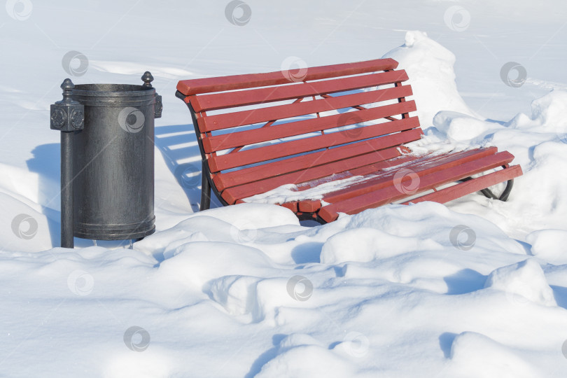 Скачать Деревянная скамейка и мусорный бак в заснеженном парке фотосток Ozero