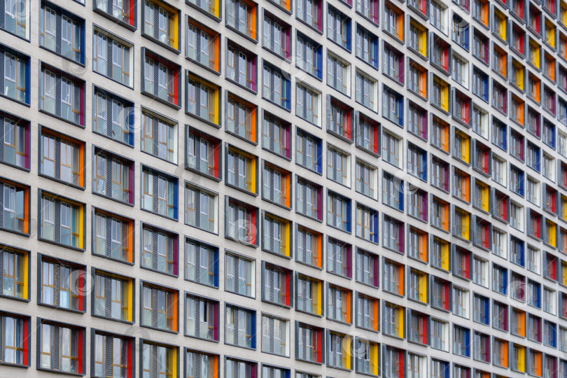 Скачать Перспективный вид фасада современного здания из бетона с цветными вставками на окнах, образующими узор, в качестве фона (абстракция) фотосток Ozero