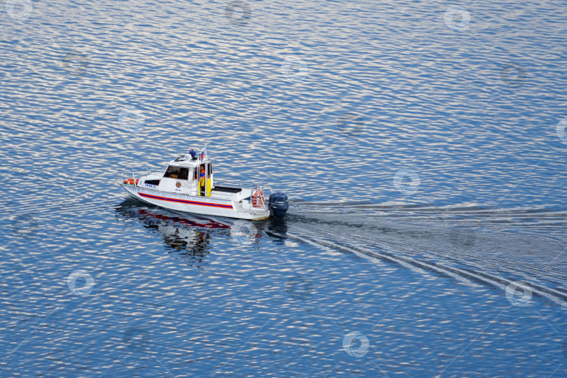 Скачать Москва-река, Россия, июнь 2018 года: Белая лодка спасательной службы на голубой воде, освещенная солнечным светом (редакционная статья) фотосток Ozero