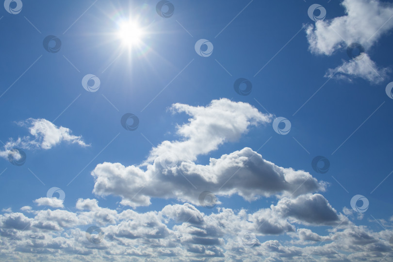 Скачать Вид пушистых облаков и полуденного солнца на темно-синем небе (задний план) фотосток Ozero