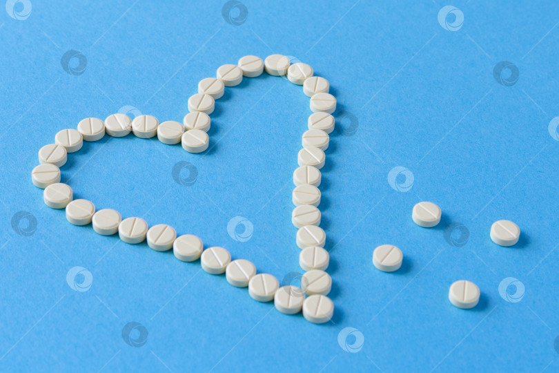 Скачать Светло-желтые таблетки выложены в форме сердца на синем фоне фотосток Ozero