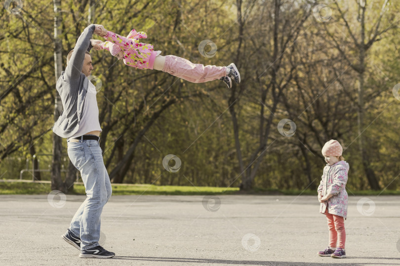Скачать Папа играет со своими дочерьми в парке. Крутил девушку вокруг себя. Семья фотосток Ozero
