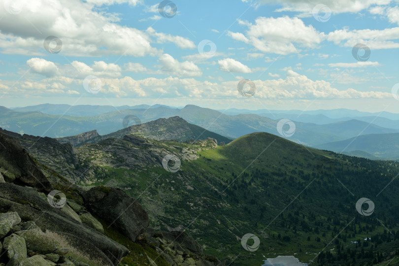 Скачать Взгляд со скалистой вершины на фрагмент живописного озера, окруженного высокими горами, под облачным летним небом. фотосток Ozero