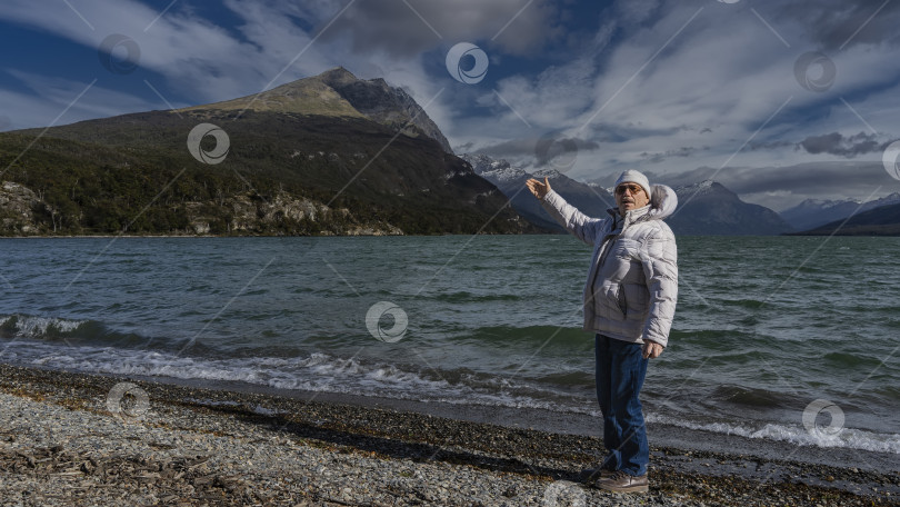 Скачать Мужчина в пуховике стоит на берегу прекрасного изумрудного озера. фотосток Ozero