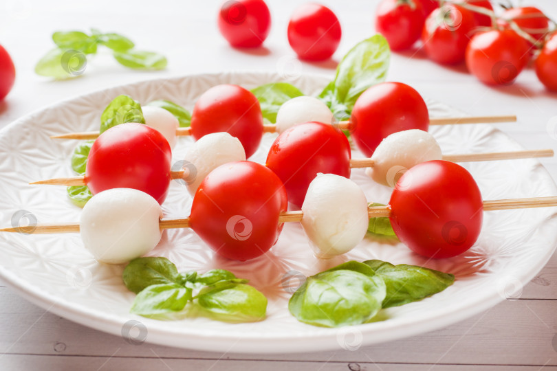 Скачать Салат капрезе из помидоров, сыра моцарелла и базилика на белой тарелке. Итальянская кухня. фотосток Ozero
