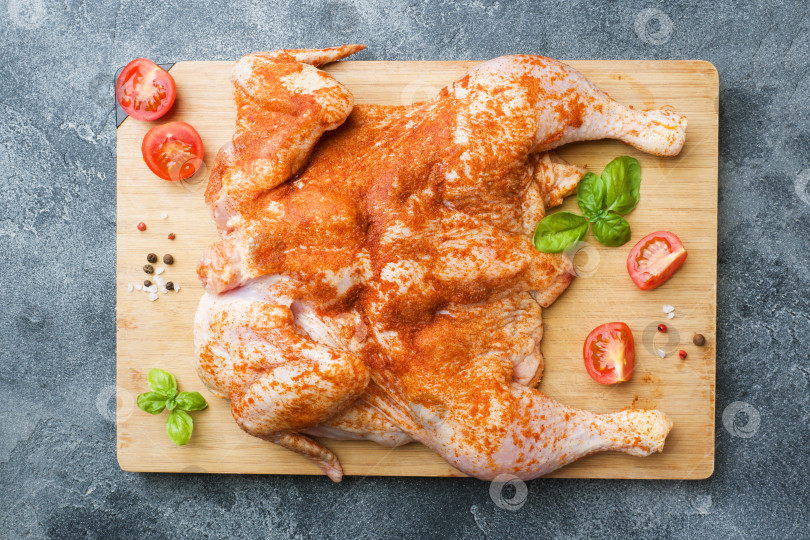 Скачать Сырая курица табака на деревянной доске со специями и овощами. фотосток Ozero