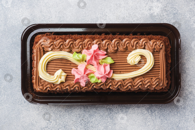 Скачать Прямоугольный шоколадный торт, украшенный кремовыми розами. Компания Sweet food занимается производством кондитерских изделий. Вид сверху фотосток Ozero