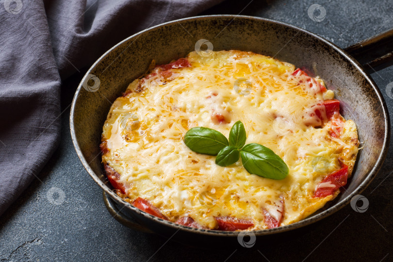 Скачать Омлет-болтунья с помидорами и сыром на сковороде на темном столе. фотосток Ozero