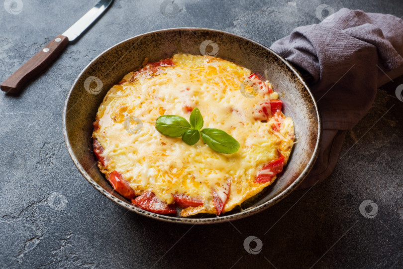 Скачать Омлет-болтунья с помидорами и сыром на сковороде на темном столе. фотосток Ozero