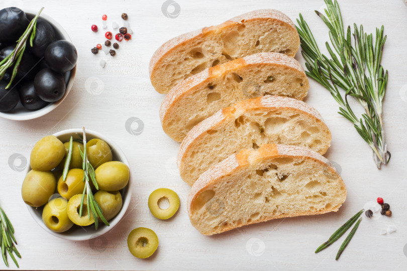 Скачать Итальянский хлеб чиабатта с оливками и розмарином на разделочной доске. Темный бетонный фон. фотосток Ozero