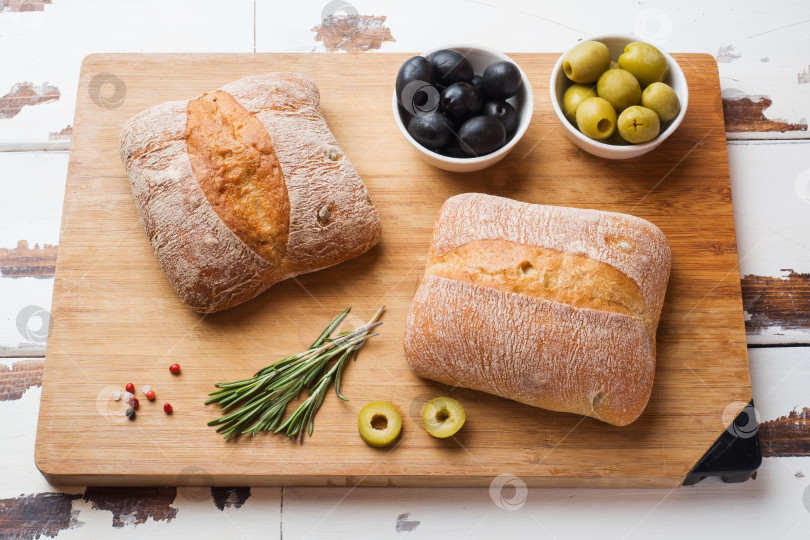Скачать Итальянский хлеб чиабатта с оливками и розмарином на деревянной доске. фотосток Ozero