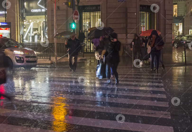 Скачать Люди переходят улицу под проливным дождем. фотосток Ozero