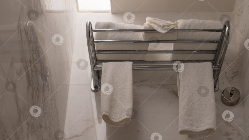 Скачать Детали интерьера ванной комнаты. Белые махровые полотенца уложены стопкой и развешаны фотосток Ozero