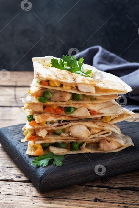 Скачать Треугольные кусочки мексиканской кесадильи с соусом. Традиционное блюдо Мексики - тортильи, фаршированные мясом и овощами. скопировать через пробел. фотосток Ozero