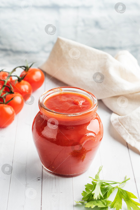 Скачать Помидоры в собственном соку или томатную пасту в стеклянной банке и свежие помидоры на белом деревянном столе. Место для копирования фотосток Ozero