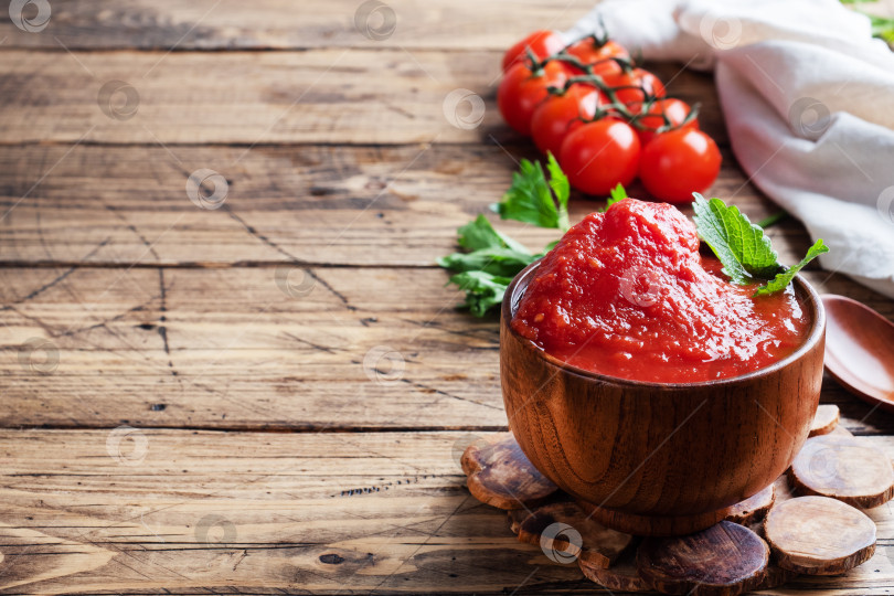 Скачать Помидоры в собственном соку или томатную пасту в деревянной миске и свежие помидоры на деревенском деревянном столе. Место для копирования фотосток Ozero