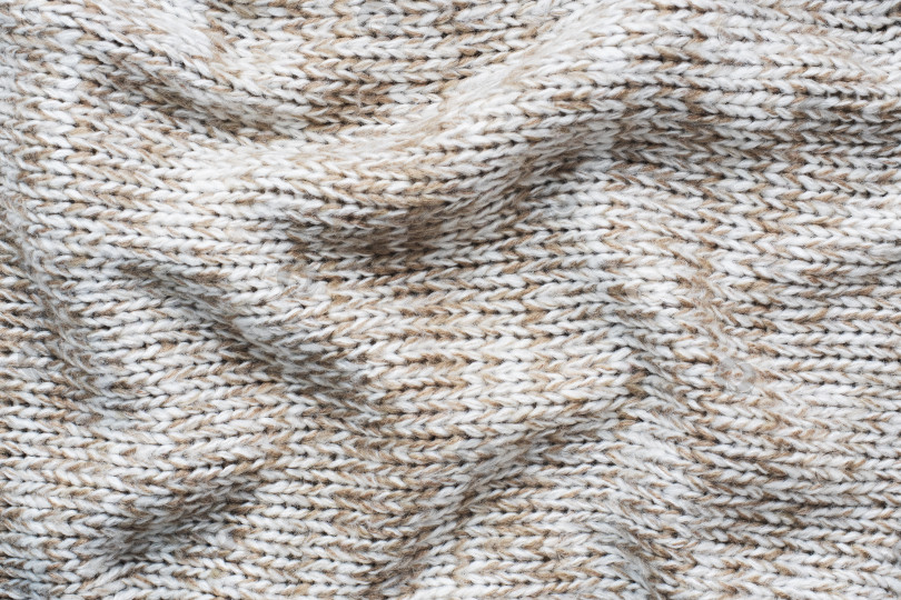 Скачать Бежевый свитер крупной вязки из натуральной шерсти с фактурой, волнистыми складками, избирательным акцентом. фотосток Ozero