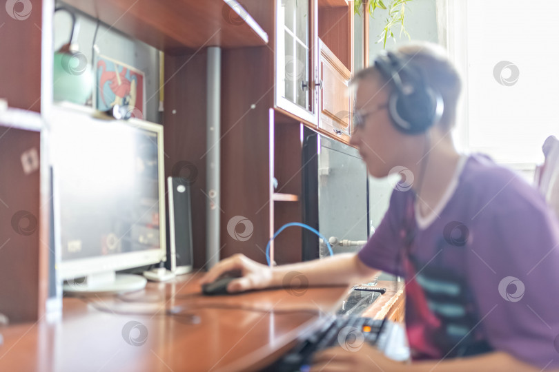 Скачать Мальчик-подросток, молодой человек, играющий в видеоигры на компьютере, использующий технологии, носящий наушники, пользующийся компьютером.Молодой человек, подросток, использующий технологию. Он играет в видеоигры. С помощью наушников. фотосток Ozero