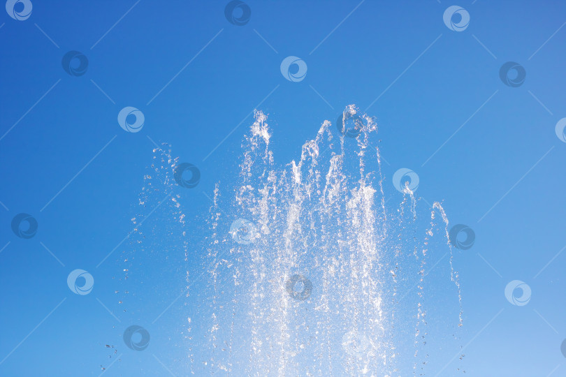 Скачать Брызги жидкости из фонтана на фоне ярко-голубого неба в природном ландшафте фотосток Ozero